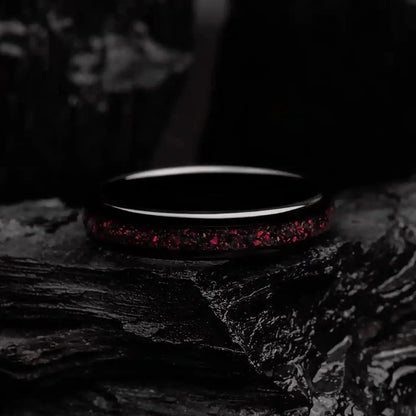 4mm black brushed tungsten ring with red opal. The ring is laying on a black coal