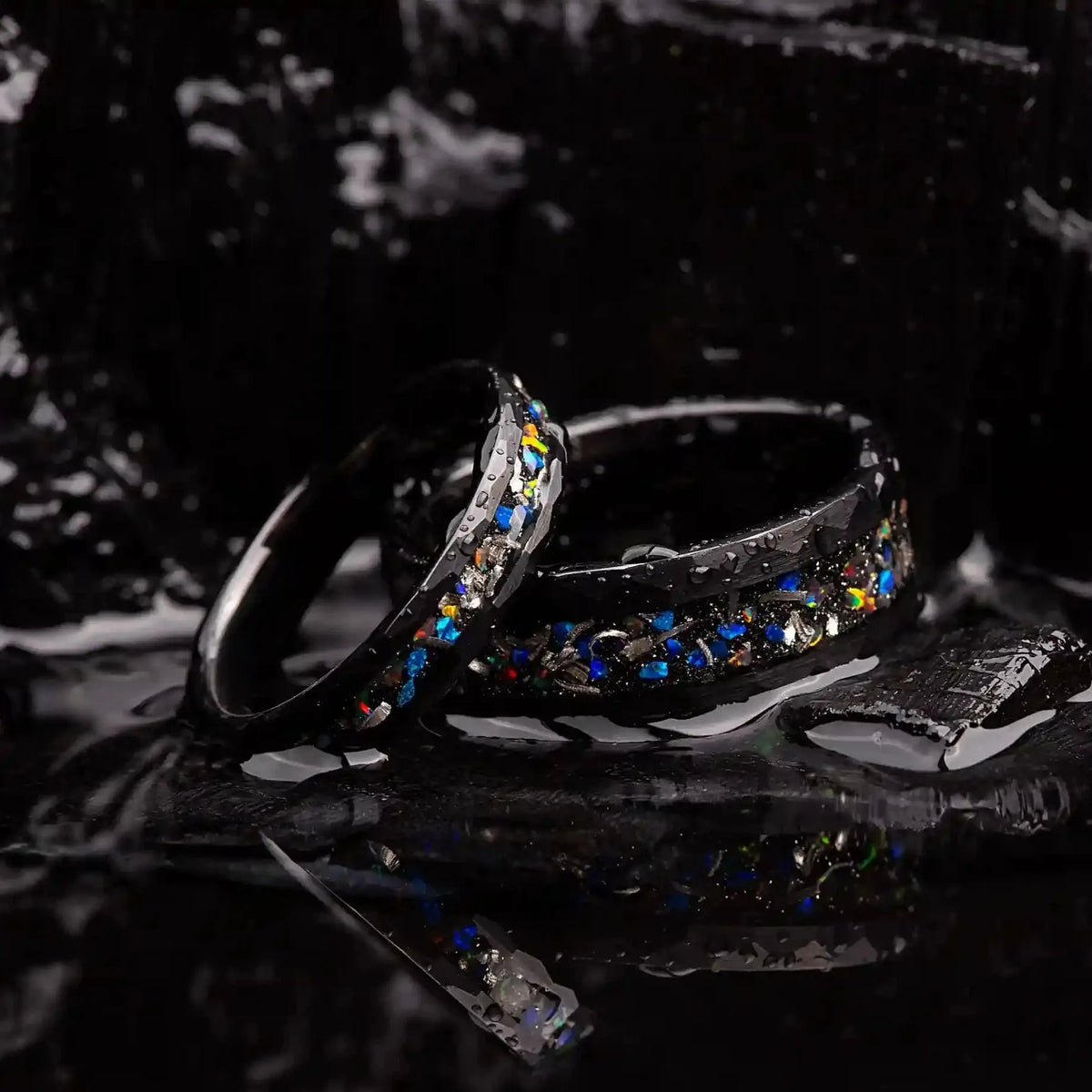 Matching wedding bands made of black hammered tungsten with galaxy opal and meteorite