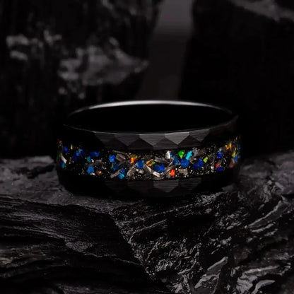 8mm black hammered tungsten ring with blue opal and meteorite. The ring is laying on a black coal
