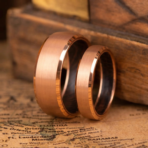 Two rose gold rings on an old map with a wooden box in the background