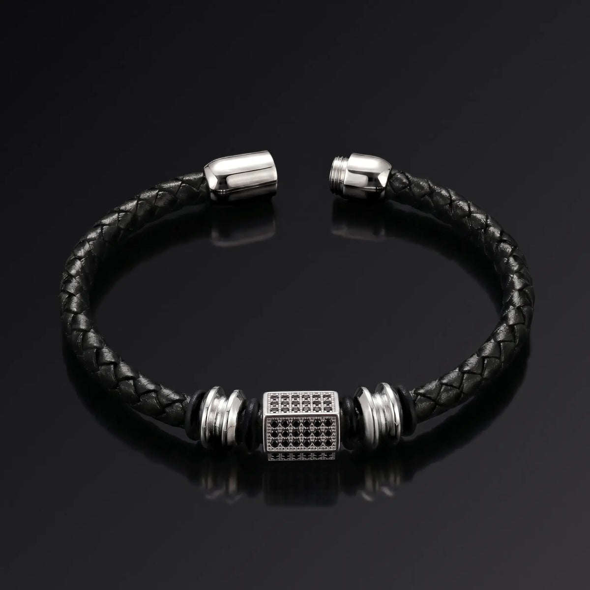 Black braided leather bracelet with silver metal clasp on a black background