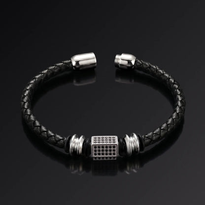 Black braided leather bracelet with silver metal clasp on a black background