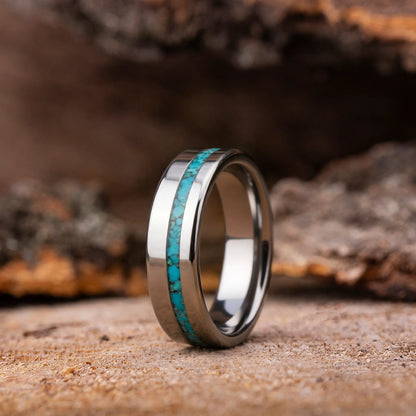 Silver ring with turquoise inlay on a wooden surface