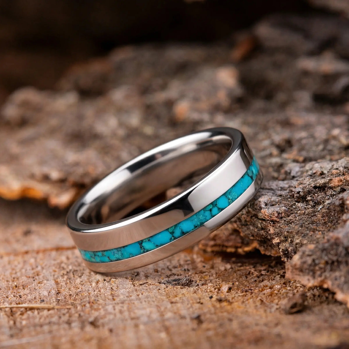 Silver ring with turquoise inlay on a wooden surface