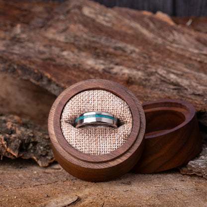 Silver ring with blue gemstone in a wooden box on a rustic wooden background
